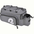 A gray heather bicycle trunk bag with a large white stylized reflective 'R' logo on the front pocket, top black bungee straps, and a side bottle holder, shown on a plain white background.