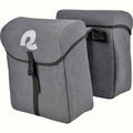 Two gray bicycle pannier saddle bags with black straps and buckles, shown on a plain white background. Featuring a white stylized reflective retrospec logo on the front flap.