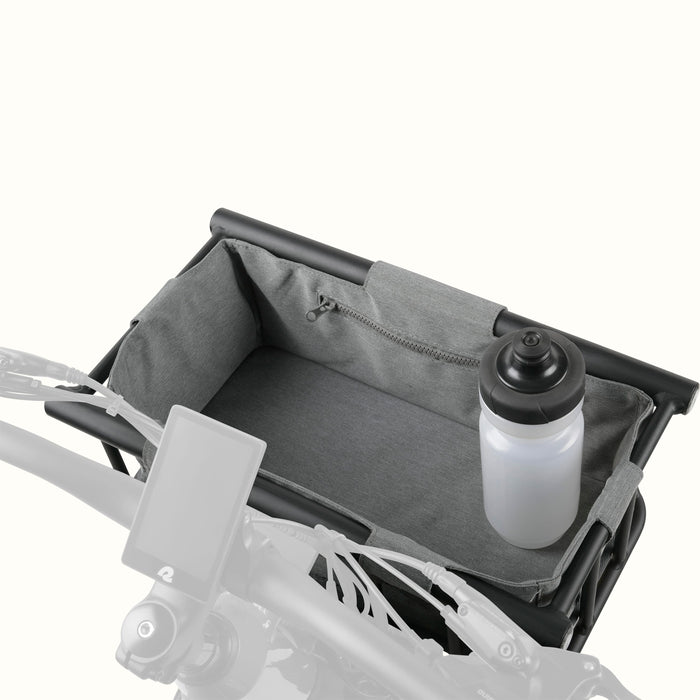 A black metal ebike basket with a grey liner and a zippered pocket, holding a water bottle, mounted on a bike's handlebars.