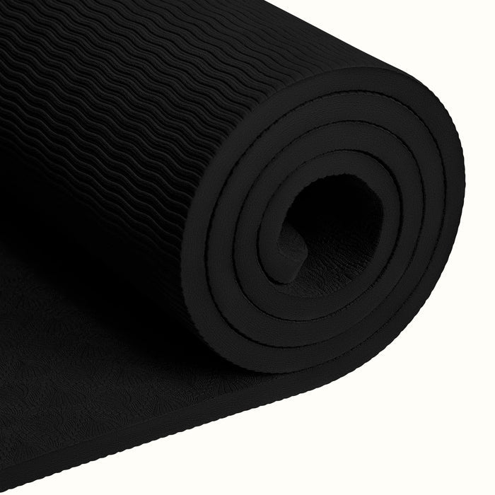Close-up of a tightly rolled black textured Zuma Yoga Mat with wavy patterned surface on a white background.